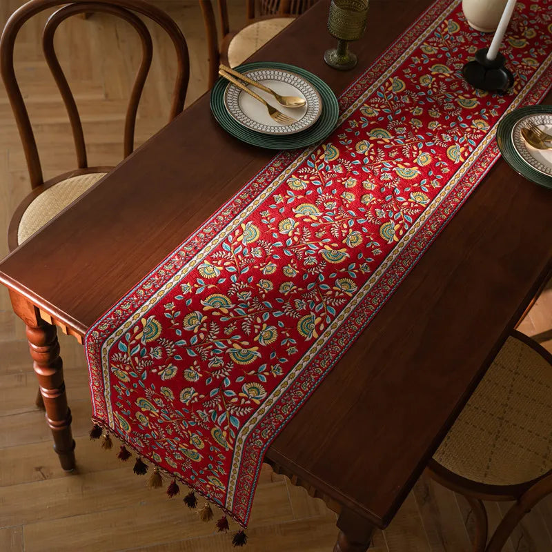 Une magnifique nappe rouge ornée de motifs floraux chatoyants, posée sur une table en bois d'un charme rustique, confère une atmosphère chaleureuse et accueillante à cette pièce.