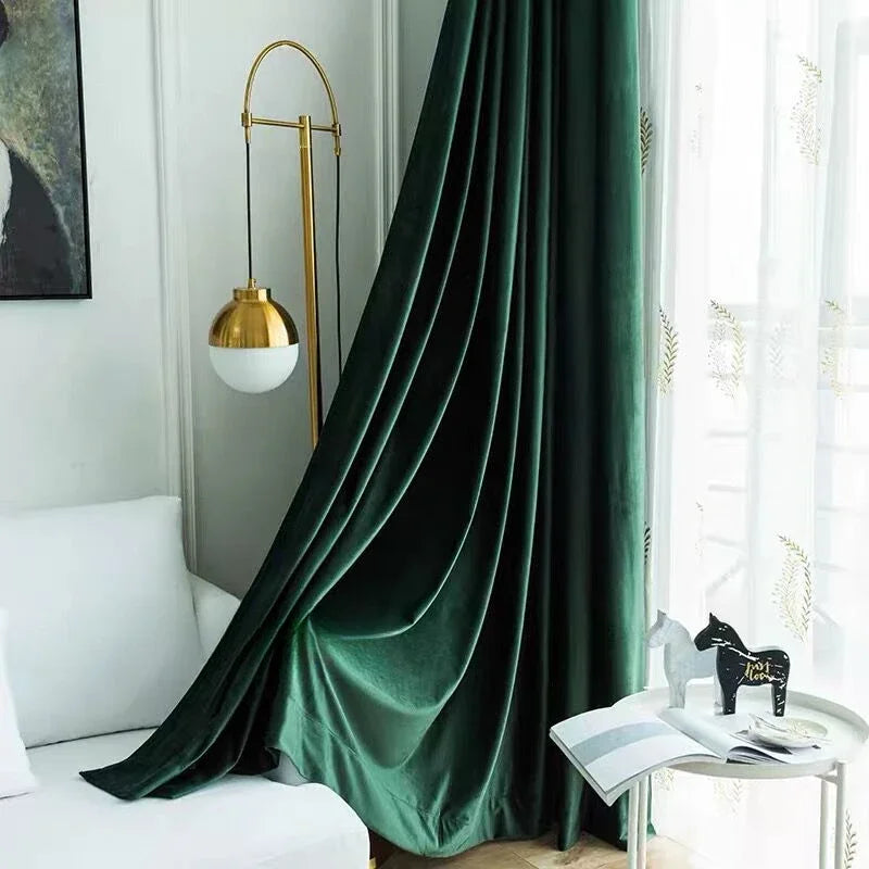 Rideau vert forêt en velours tombant avec fluidité dans un salon lumineux au mobilier blanc, ambiance moderne et chaleureuse.