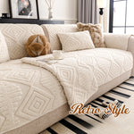 L'image montre un canapé confortable et douillet recouvert d'un plaid aux motifs géométriques beiges, accompagné de coussins décoratifs et d'un vase avec des branches, dans un décor de style rétro.