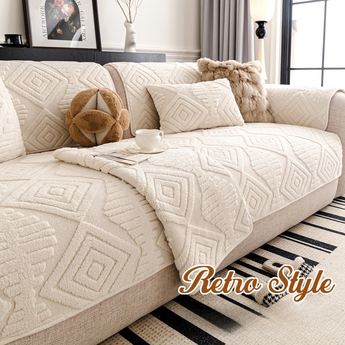 L'image montre un canapé confortable et douillet recouvert d'un plaid aux motifs géométriques beiges, accompagné de coussins décoratifs et d'un vase avec des branches, dans un décor de style rétro.