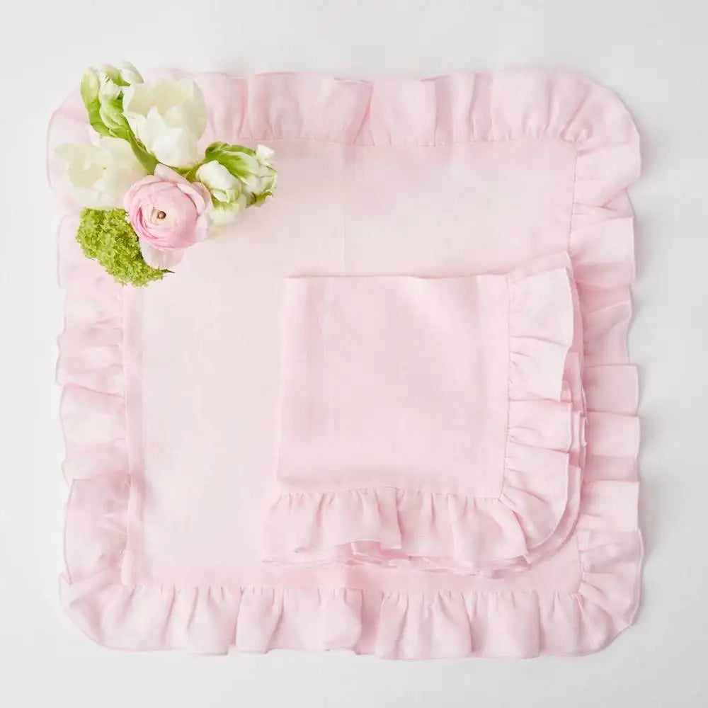 Une composition florale élégante avec des roses délicates et des fleurs blanches sur un fond rose pastel aux froufrous.
