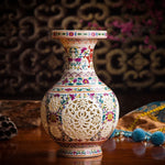 Vase décoratif en céramique ornée de motifs floraux colorés et de découpes ajourées créant un design élégant et raffiné.