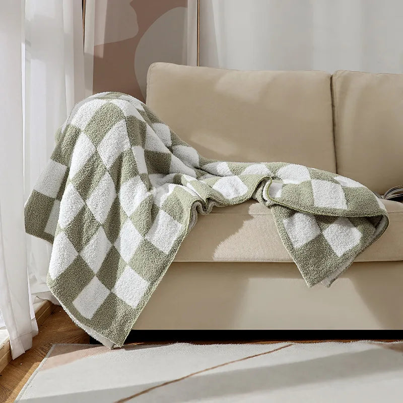 Une couverture de sol beige et blanche texturée est posée sur un canapé moelleux, créant une ambiance cocooning dans cette pièce.