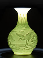 Vase décoratif en verre translucide de couleur jaune pâle avec un motif en relief représentant des oiseaux et des fleurs.