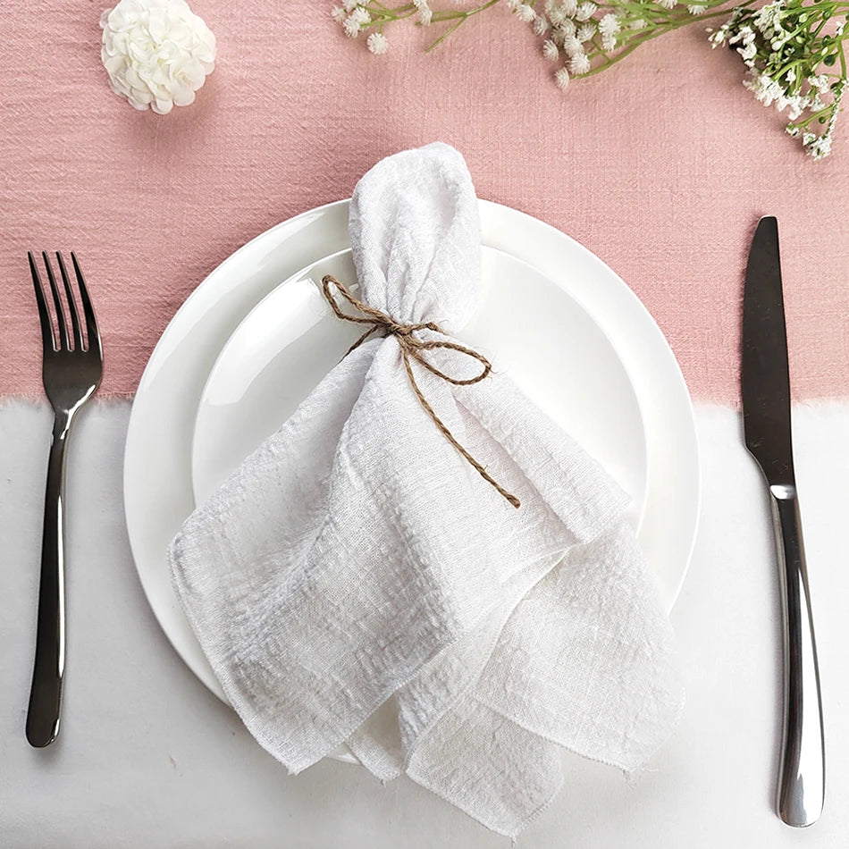 Une table élégante avec des assiettes blanches, des couverts et des fleurs sur un fond rose pastel.