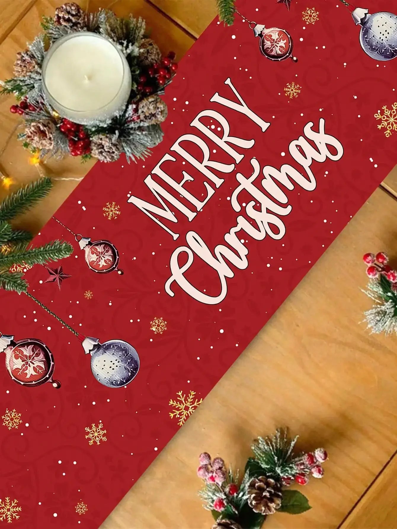 Décoration de Noël avec un grand texte rouge et blanc "Merry Christmas" sur un fond à motifs de flocons de neige, accompagné de branches de sapin et de pommes de pin.