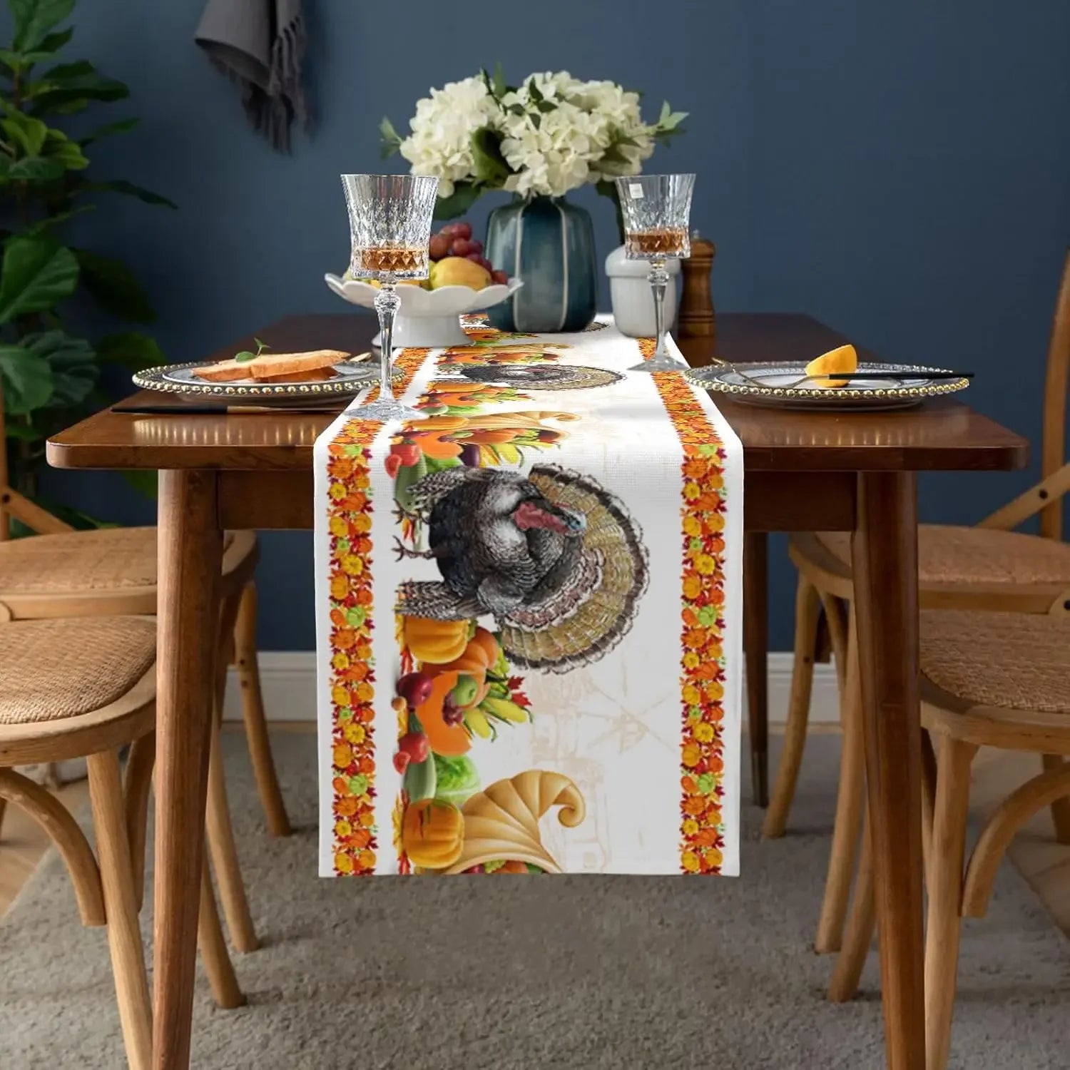 Le centre de table de fête d'automne présente une composition élégante avec des bouquets de fleurs blanches, des verres à vin et des assiettes décorées de motifs de feuilles et de dinde.