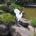 Statue de grue en résine grise dans un jardin