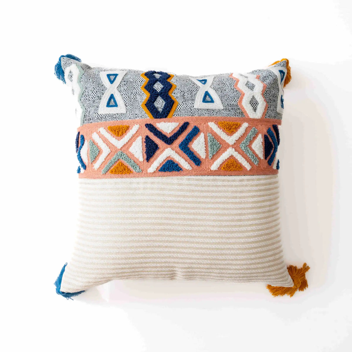 Coussin décoratif de style ethnique avec motifs géométriques colorés sur fond gris et blanc, avec des franges aux coins pour une touche bohème.