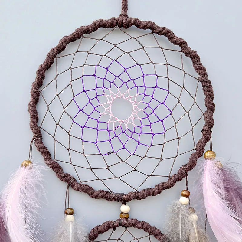 Un capteur de rêve décoratif aux tons pourpres et dorés, avec une structure en macramé complexe et délicate.