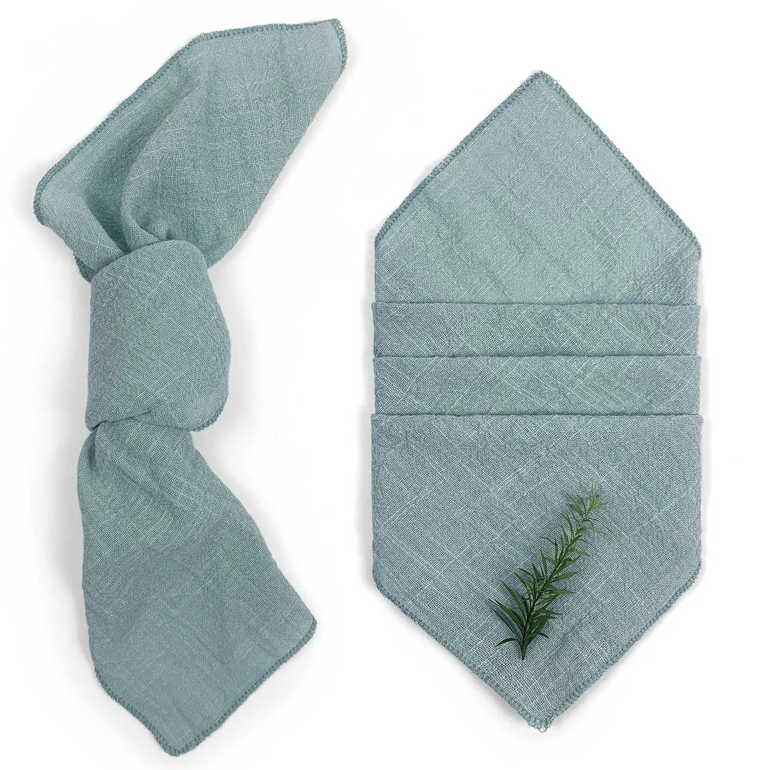 Serviette pliée verte pâle avec un ornement de branche de conifère, suggérant une ambiance apaisante et naturelle.