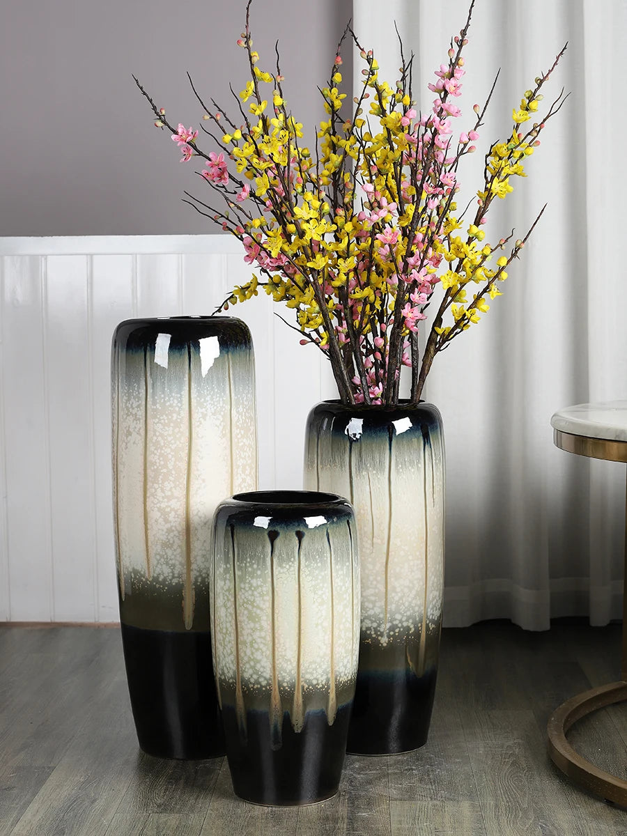 Vase en céramique noir et blanc avec bouquet de branches à fleurs jaunes et roses.