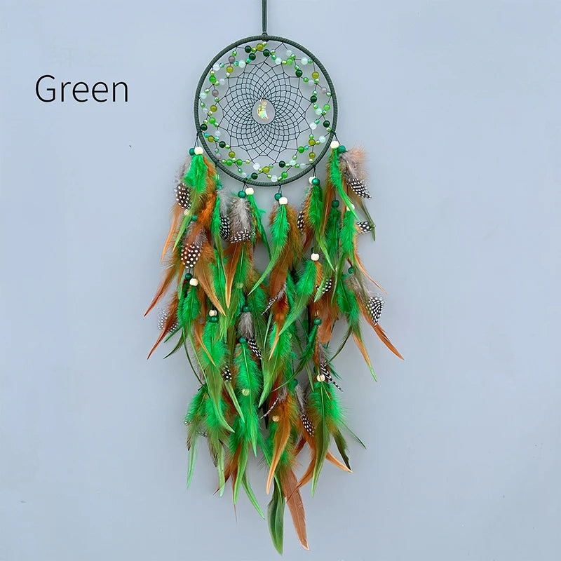 Un attrape-rêves décoratif aux teintes vertes, composé de plumes multicolores et de perles scintillantes, suspendu sur un fond blanc.