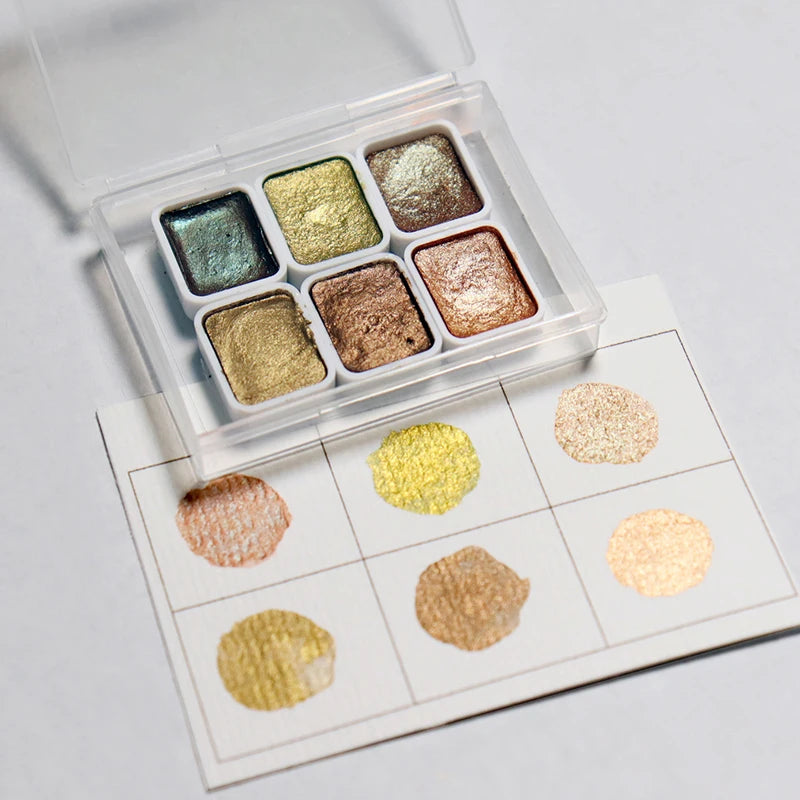 peintures aquarelle palette compacte bleu vert violet rose beige jaune blanc texture granuleuse opaques