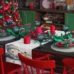 Réunion festive et chaleureuse pour les fêtes de Noël, avec des décorations rouges et vertes, des bougies allumées et un bonhomme de neige souriant sur la table.