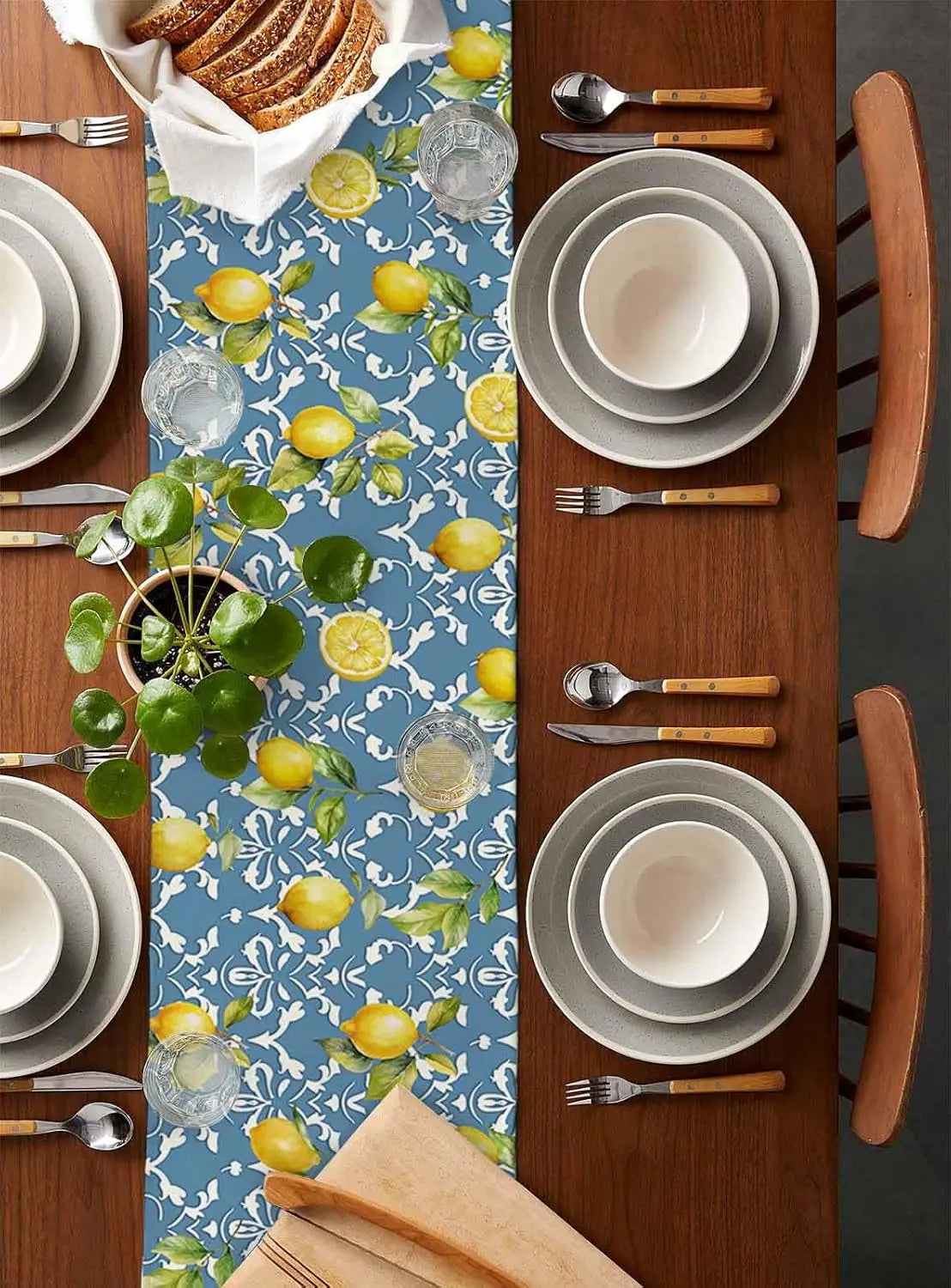 Une table élégante, au motif de citrons frais et de feuillage vert sur un fond bleu, avec des assiettes et des couverts en bois, prête pour un repas délicat et savoureux.