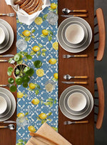 Une table élégante, au motif de citrons frais et de feuillage vert sur un fond bleu, avec des assiettes et des couverts en bois, prête pour un repas délicat et savoureux.