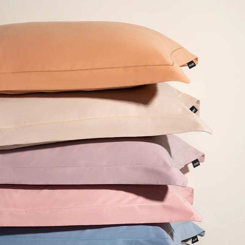 Des oreillers en coton de différentes teintes pastel, empilés les uns sur les autres, avec des fermetures éclair apparentes.