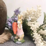 Une délicate figurine de lapin en porcelaine tenant une carotte, entourée de belles fleurs.