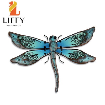 Décoration murale libellule en métal multicolore sur mur de jardin