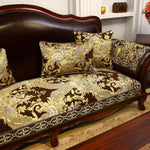 Un canapé vintage en bois foncé avec des coussins ornés de motifs floraux dorés et foncés, créant une ambiance chaleureuse et élégante dans cette pièce.