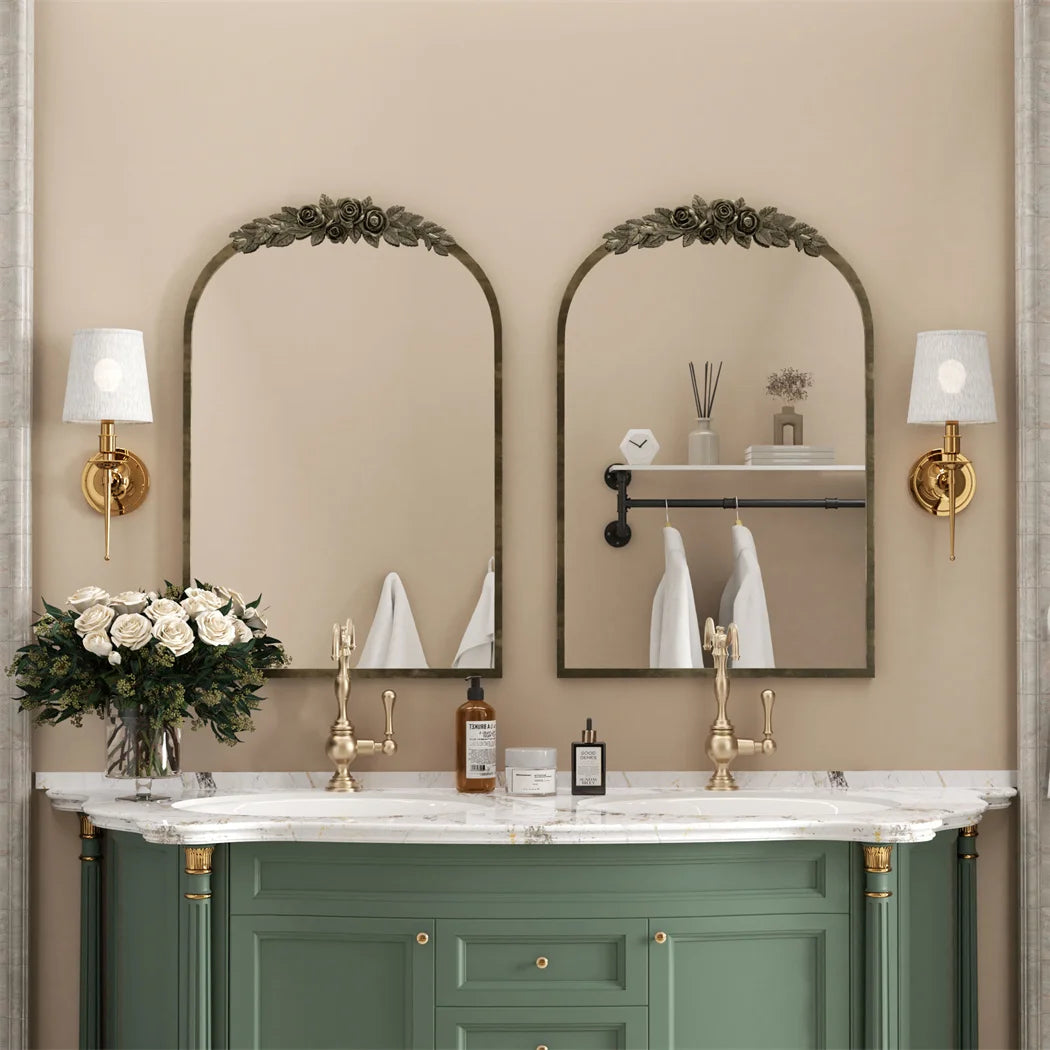 Salle de bain élégante avec deux miroirs muraux ornés de motifs floraux, un grand meuble-lavabo en vert avec un plan de travail en marbre blanc, et des accessoires de salle de bain sur le dessus.