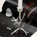 Photophore en métal argenté représentant une branche d'arbre avec un oiseau perché, donnant un aspect élégant et naturel à la décoration.