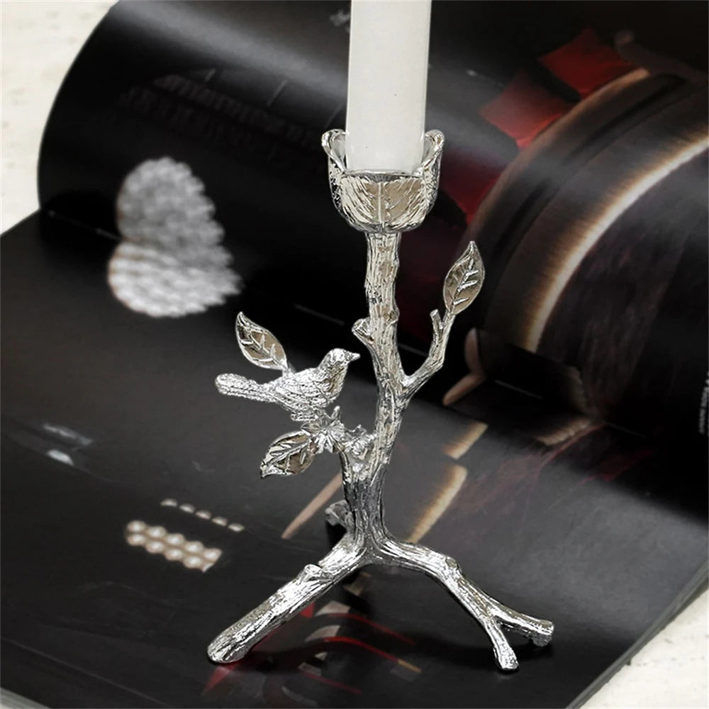 Photophore en métal argenté représentant une branche d'arbre avec un oiseau perché, donnant un aspect élégant et naturel à la décoration.