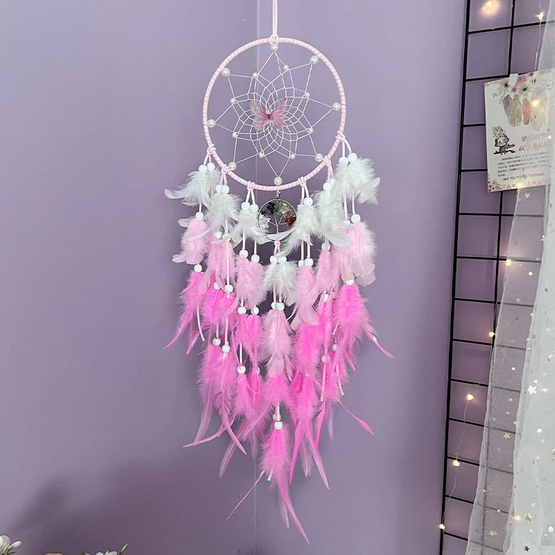 Un attrapeur de rêves décoratif rose et blanc, suspendu sur un fond violet, ornée de plumes délicates et d'un centre en forme de fleur.