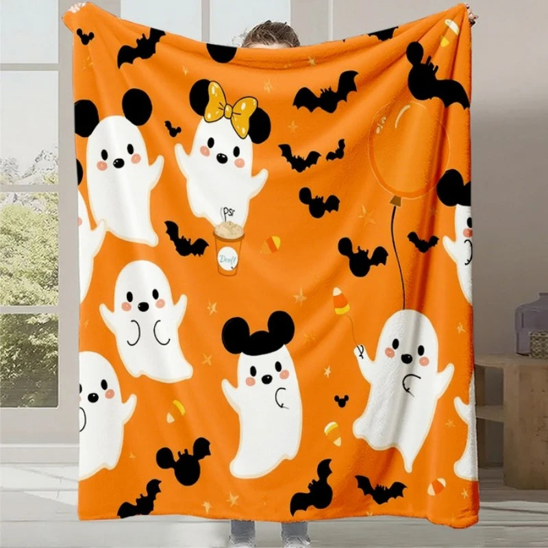 Une couverture moelleuse et festive mettant en scène des fantômes de Mickey Mouse sur un fond orange et décoré de chauves-souris noires, créant une ambiance Halloween chaleureuse et amusante.