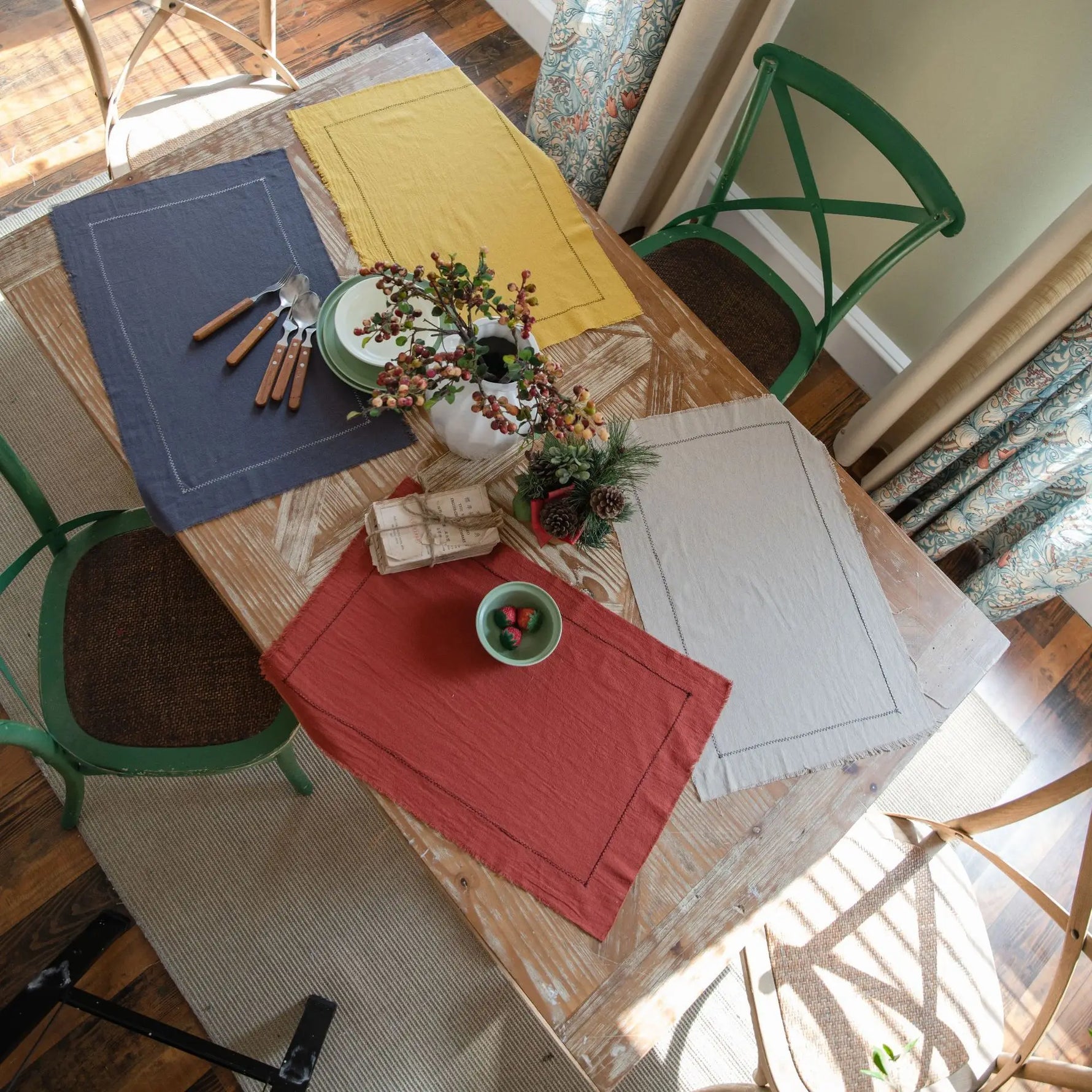 Sur une table en bois rustique, un ensemble décoratif de tissus, de fleurs et d'accessoires crée une ambiance chaleureuse et accueillante.