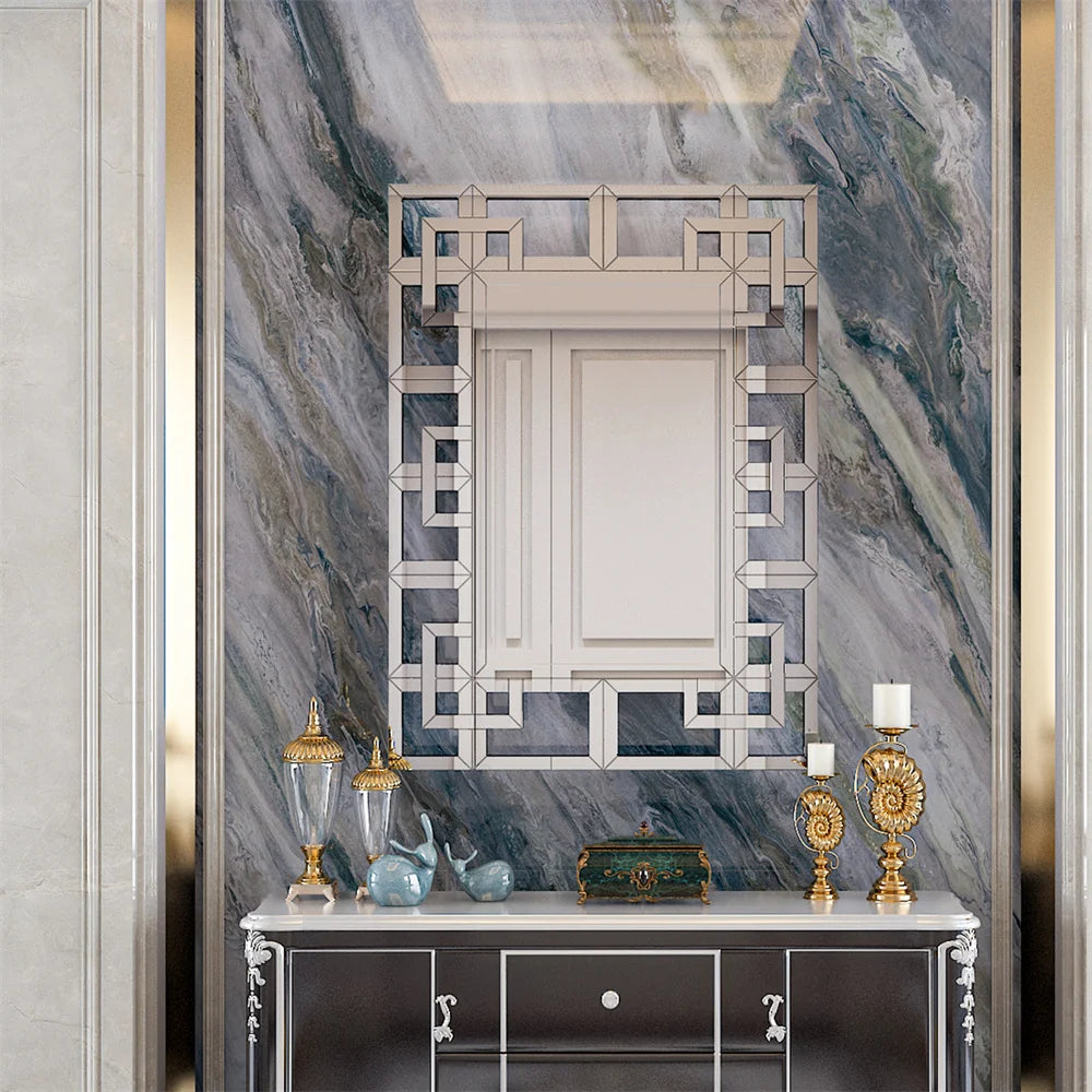 Une console élégante ornée de décorations dorées et d'un miroir géométrique est placée devant un mur de marbre gris, créant une atmosphère luxueuse et raffinée.