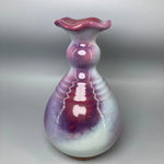 Vase vintage de forme arrondie en céramique avec une texture et une couleur violette et rose, une forme fluide et ondulée.