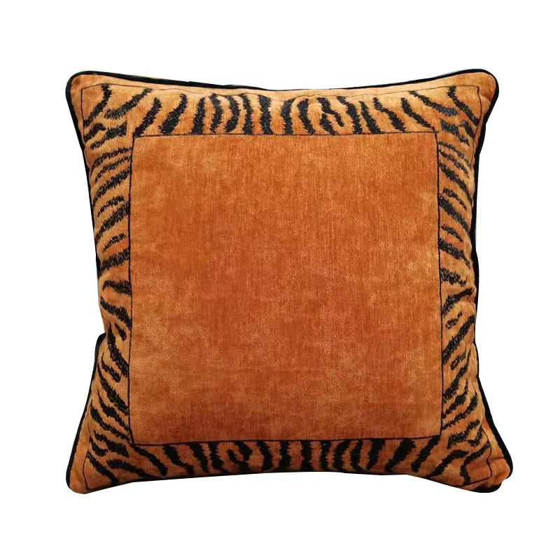 Coussin décoratif carré en velours orange avec bordure imprimée motif zébré dans des teintes marron et noir.