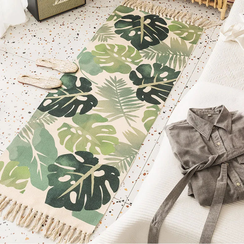 Tapis décoratif orné de motifs tropicaux stylisés en vert, beige et noir, posé à côté d'un amplificateur de guitare et d'une chemise en jean dans un intérieur élégant.