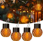 Lanterne solaire LED effet flamme orange allumée dans un jardin le soir
