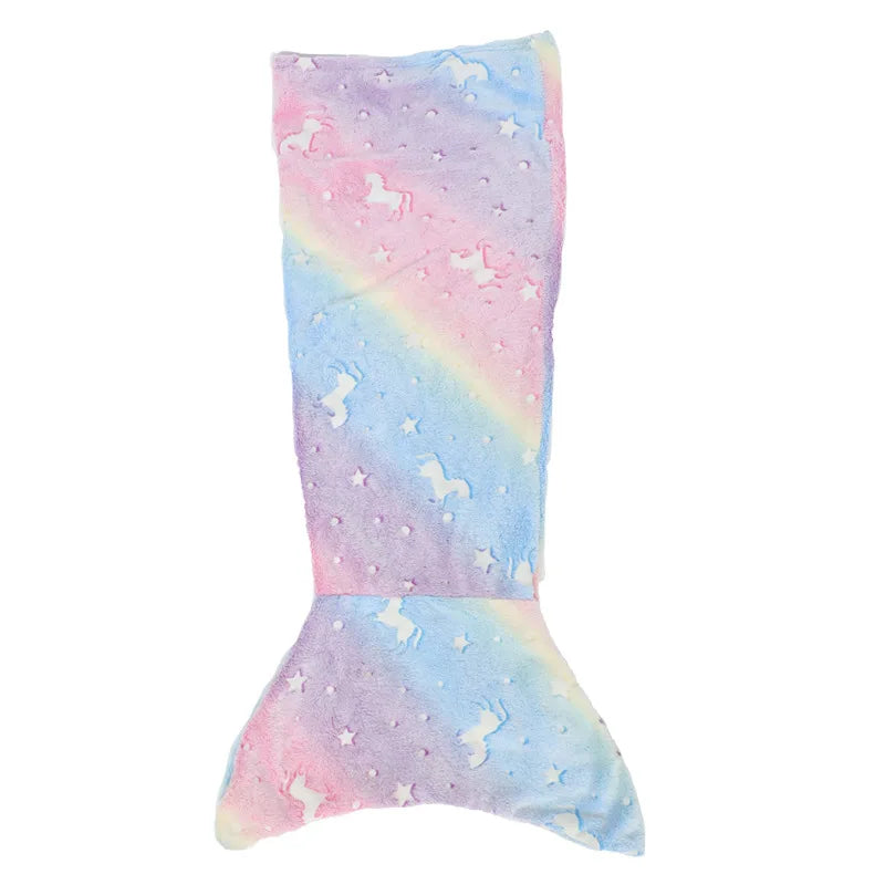 Une queue de sirène en peluche douce et colorée, avec des motifs de licornes et d'étoiles sur un arrière-plan arc-en-ciel.