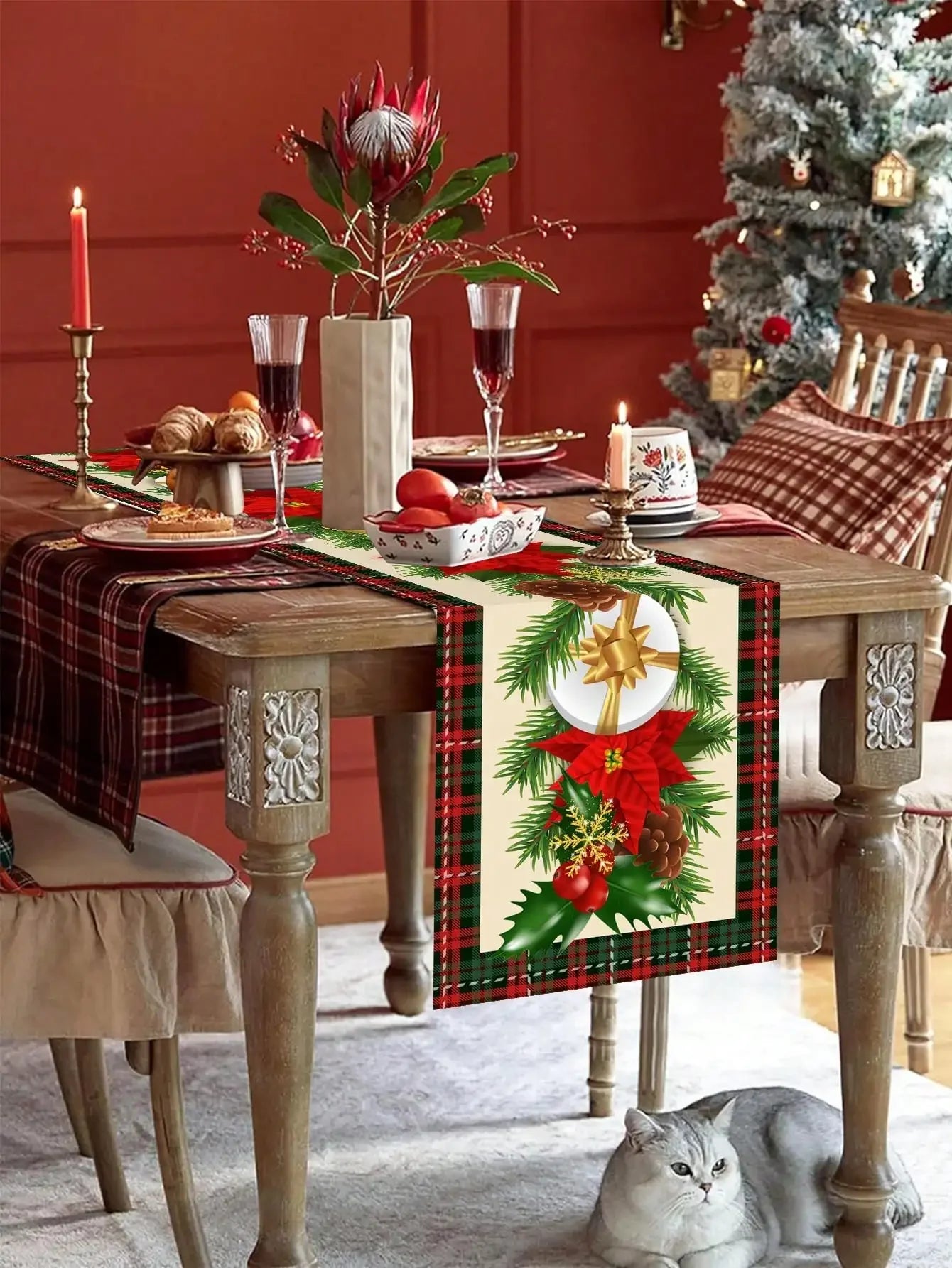 Une table de Noël joliment décorée avec des fleurs, des verres de vin et des plats traditionnels, devant un sapin enneigé.