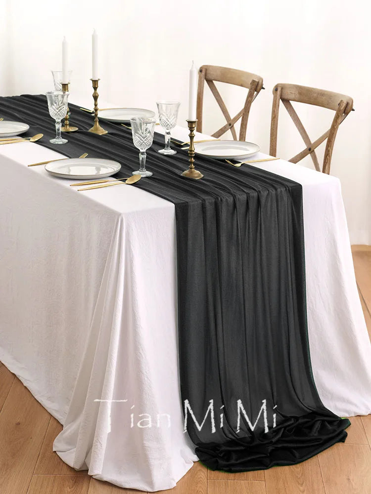 Une table de salle à manger élégante avec des nappes blanches et noires, des chaises en bois, des verres et des bougies, créant une ambiance chaleureuse et raffinée.