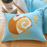 Un coussin bleu avec un motif en forme de gâteau roulé, représentant un snack délicieux et réconfortant.