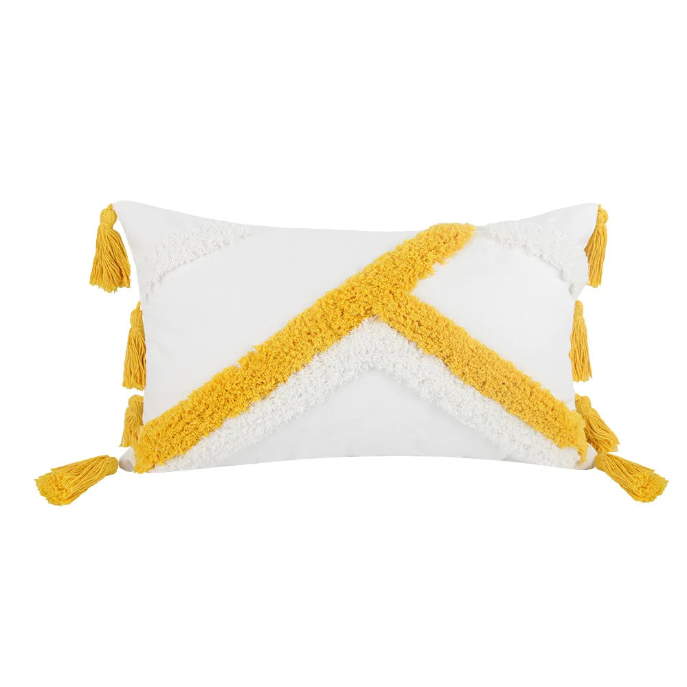 Oreiller décoratif blanc et jaune avec des glands décoratifs.