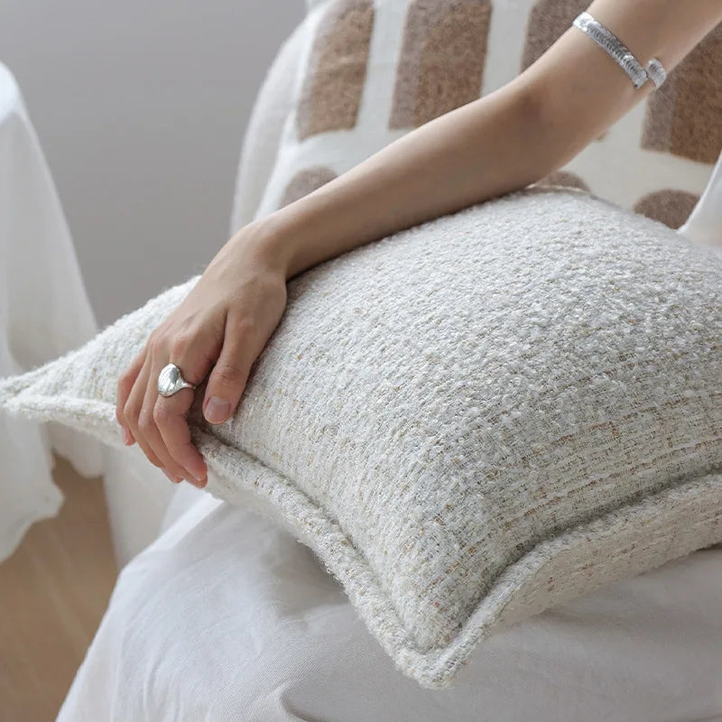L'image montre des mains posées sur un coussin gris moelleux, avec un bijou en argent sur un des doigts.