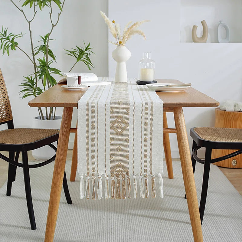 La table de salle à manger en bois avec un chemin de table texturé et décoratif donne un aspect confortable et harmonieux à cette pièce remplie de plantes verdoyantes.