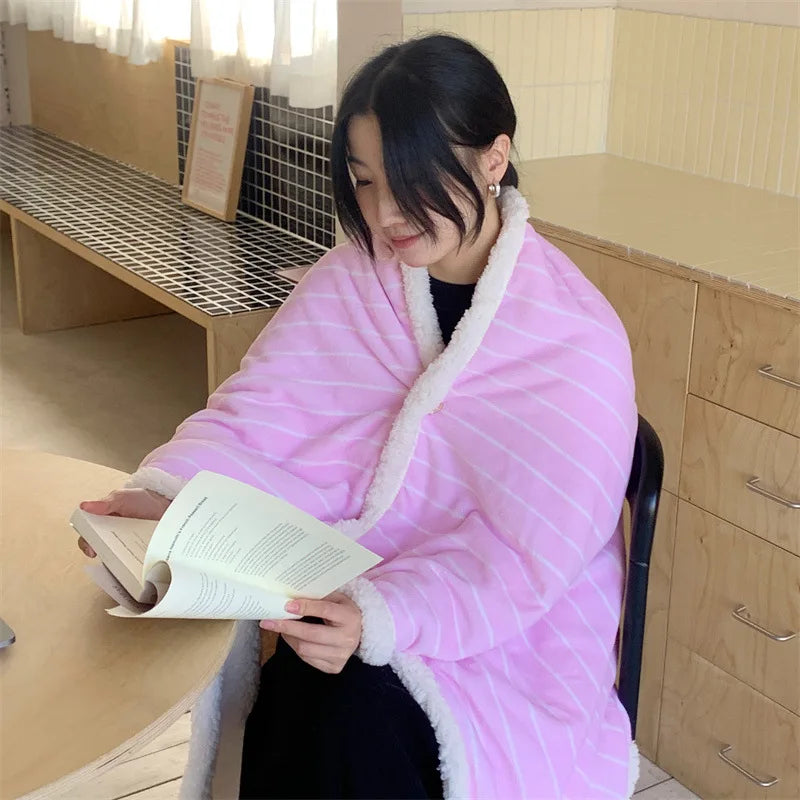 Une femme dans un gilet rose tricoté semble lire un livre sur son lieu de travail.