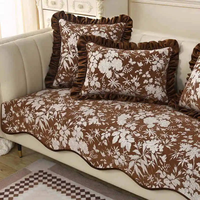 Coussins et dessus de lit décoratifs à motifs floraux bruns et blancs, créant une ambiance chaleureuse et confortable dans cette pièce.