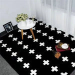 Une table ronde blanche et un tapis noir motif croix blanches ornent cette pièce élégante et moderne.