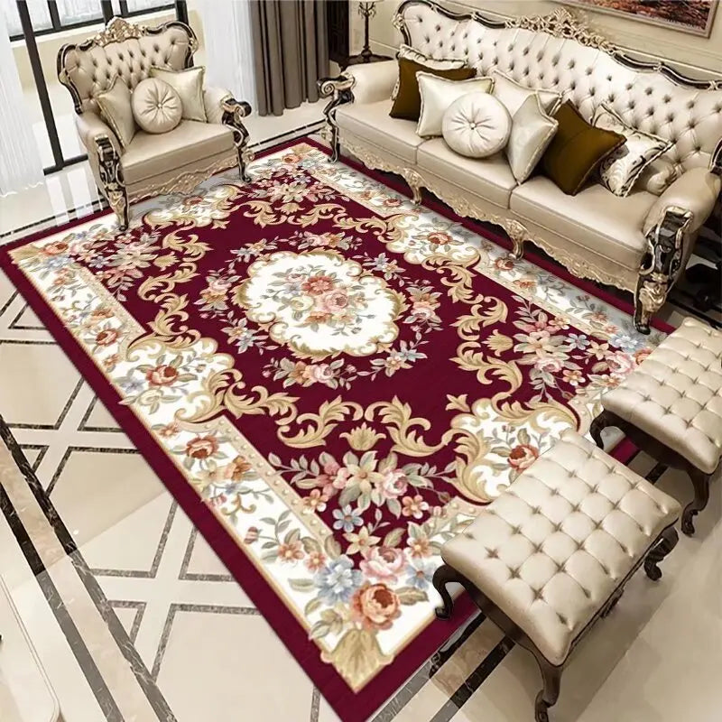 Le salon contient un canapé galbé à capitonnage beige et des fauteuils assortis, posés sur un tapis rouge foncé aux motifs floraux élégants, créant une atmosphère raffinée et chaleureuse.