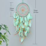 Un capteur de rêves décoratif en plumes de couleur vert menthe, mesurant 76 cm de hauteur et comprenant des perles oranges.