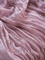 Une texture drapée de soie rose pâle, aux plis élégants et délicats, créant une impression de douceur et de raffinement.