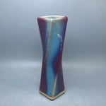 Un vase de céramique aux couleurs irisées et ondulantes, créant un effet visuel élégant et captivant.